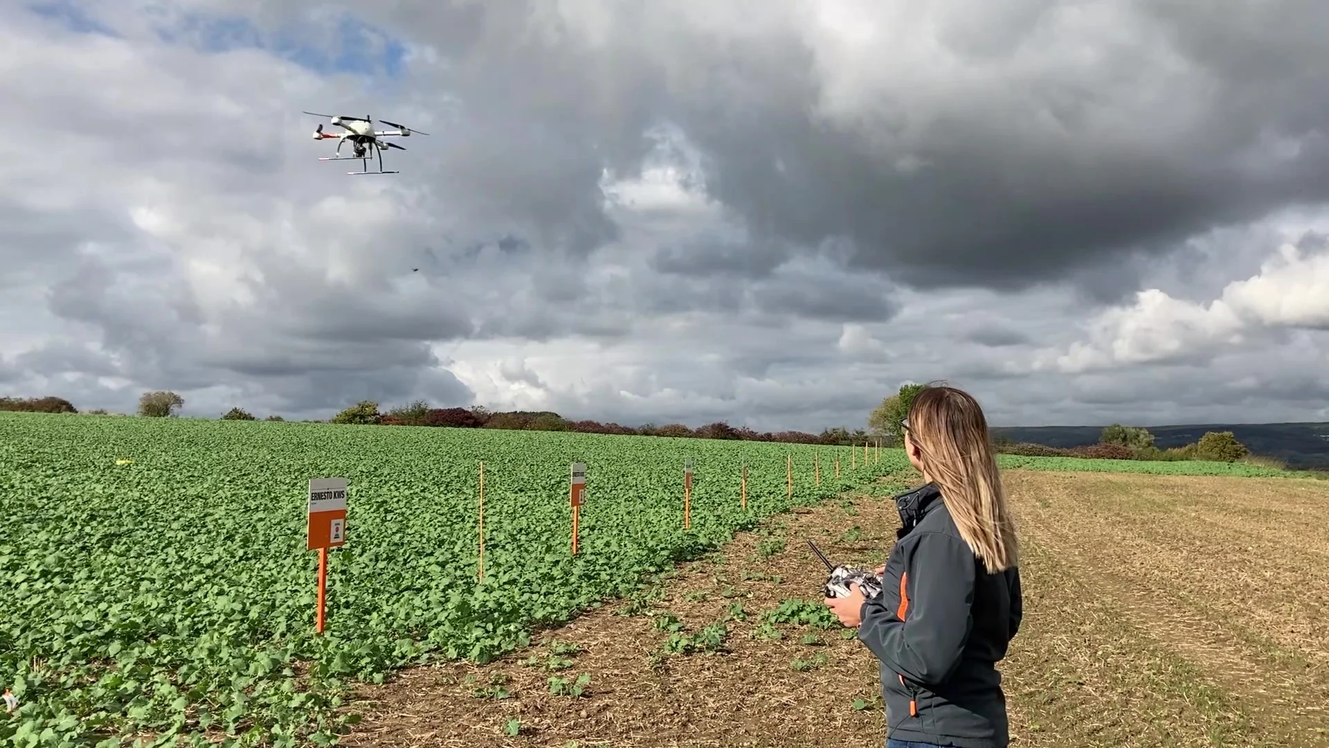 An inspection drone patrolling an experimental field with its operator.